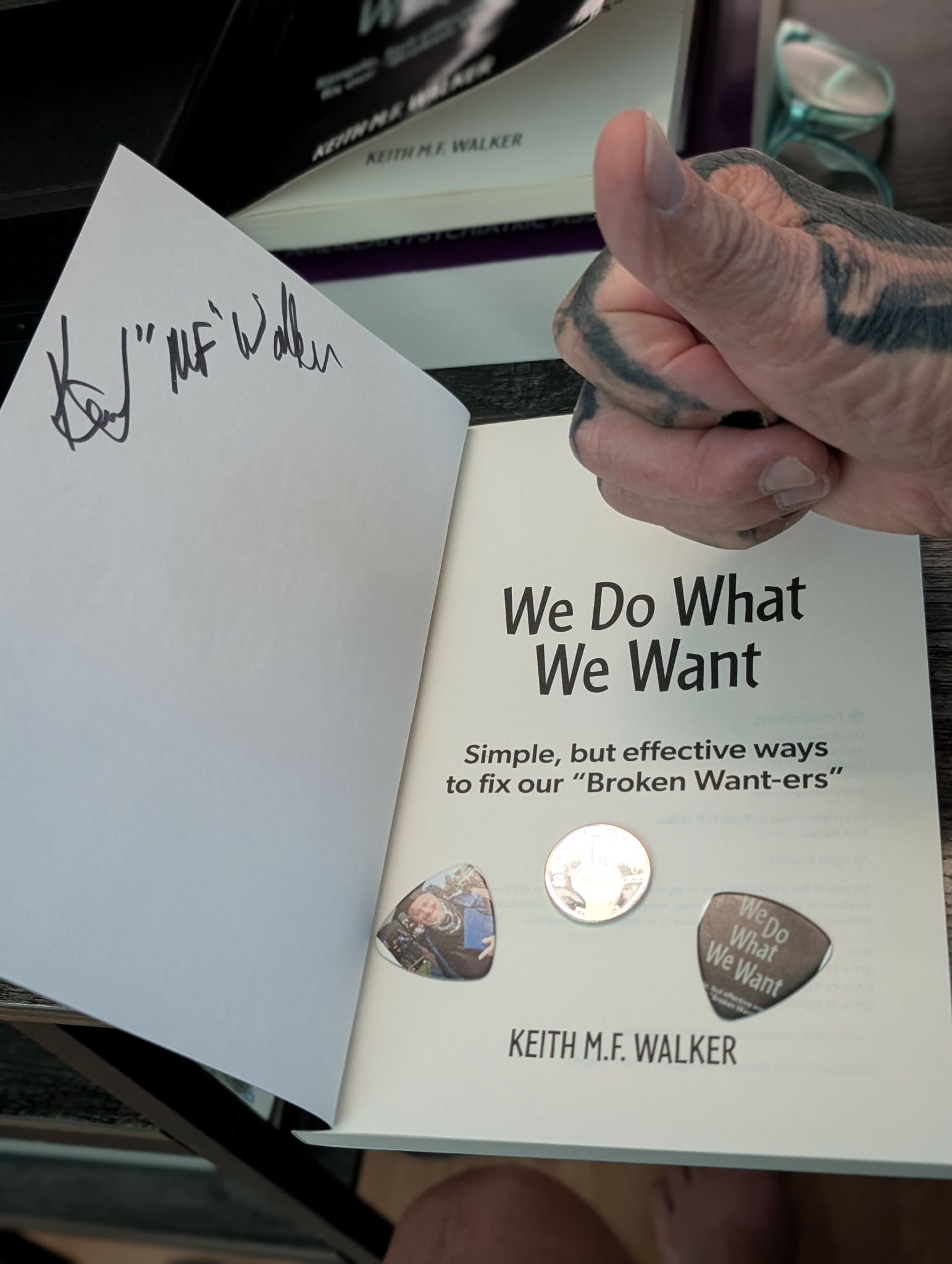 Signed copy of We Do What We Want by Keith MF Walker — open to the title page with Keith's signature and guitar picks